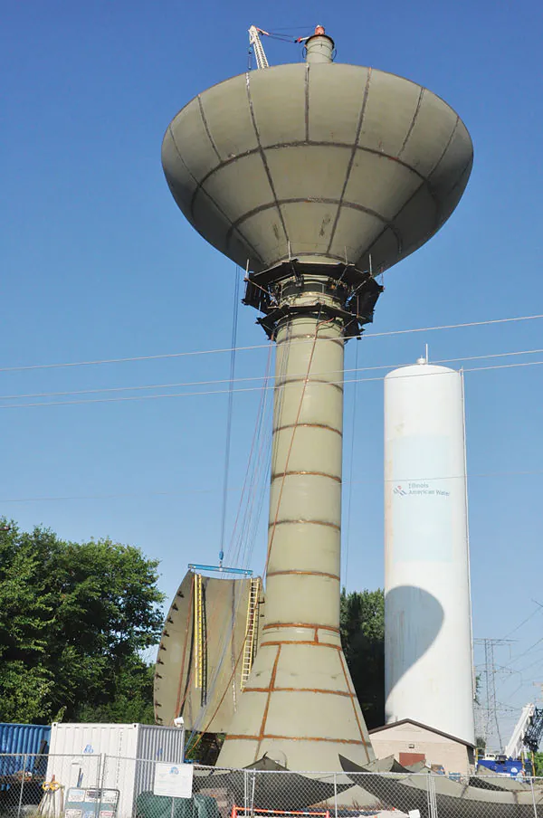 A water tower under construction, with its steel bowl supported on a partially assembled column.